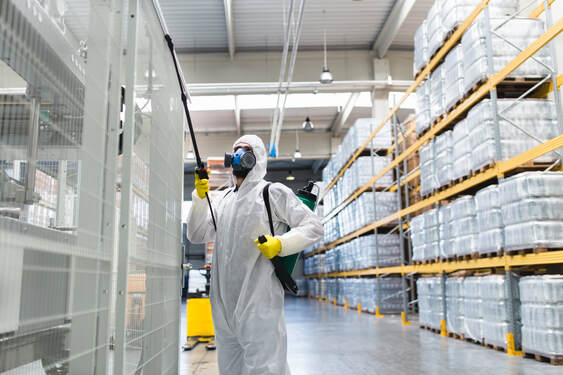 Worker spraying for bugs in warehouse